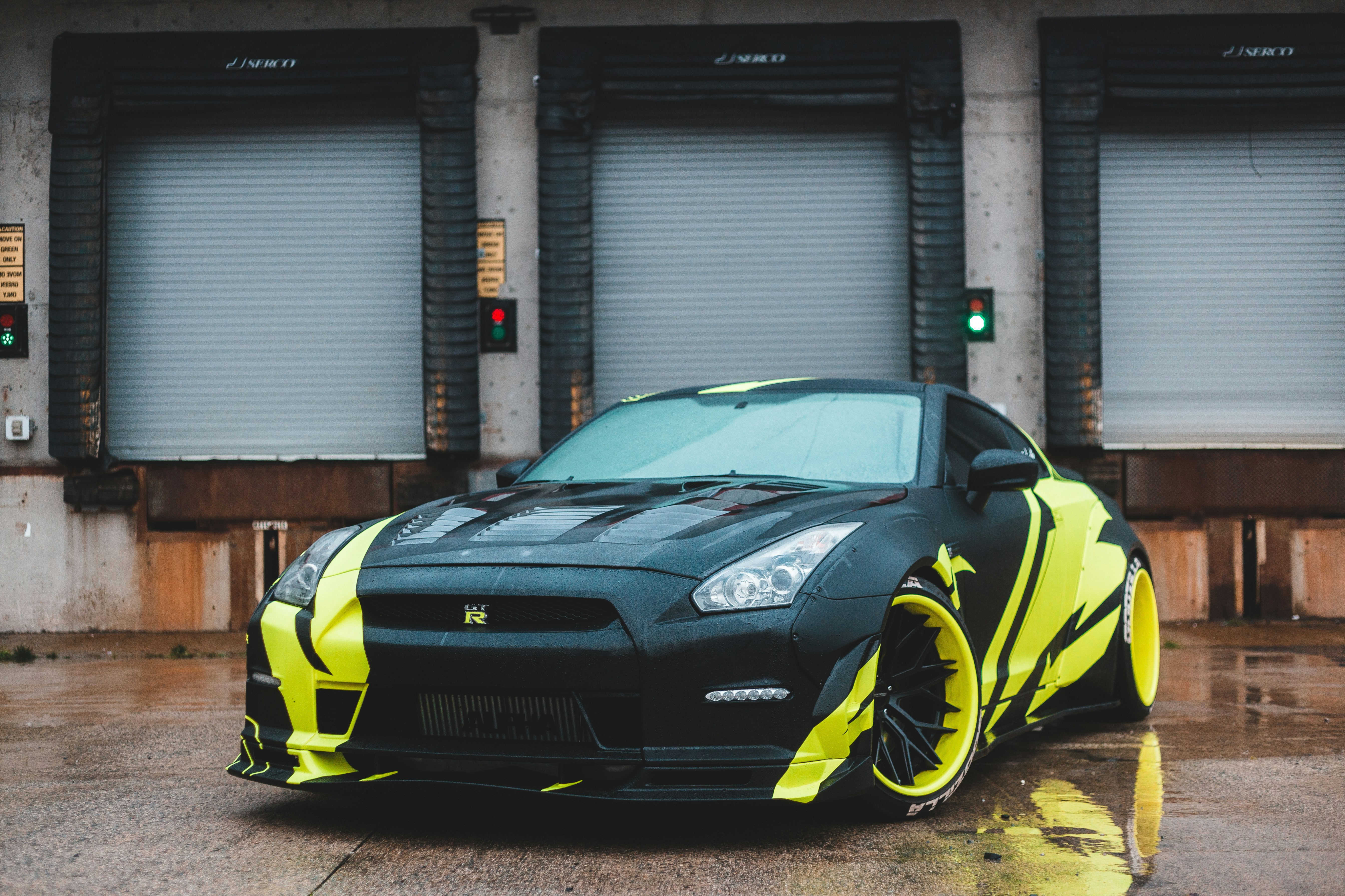 black and yellow lamborghini aventador parked beside gray steel roll up door